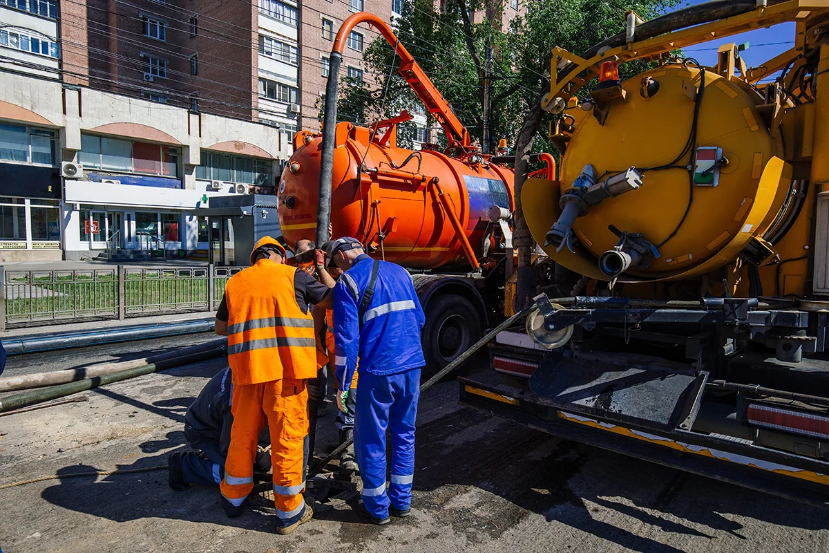 Eures • Arbeiter reparieren Rohrleitungen mit technischen Fahrzeugen im Hintergrund.