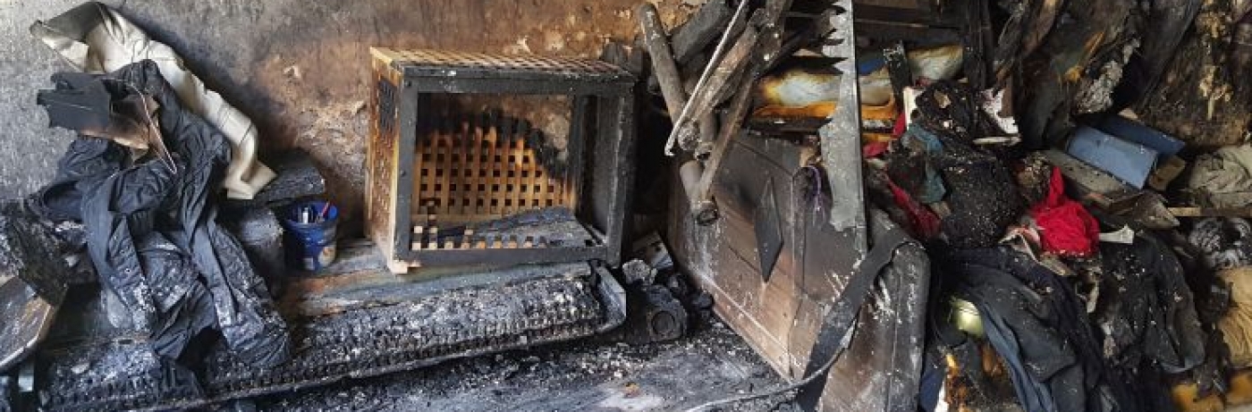 Eures • Zerstörte Wohnung nach Brand; verkohlte Möbel und Kleidungsstücke sichtbar.
