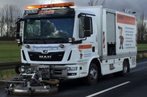 Eures • Ölspur-Beseitigungsfahrzeug auf Straße mit Reinigungstechnik.