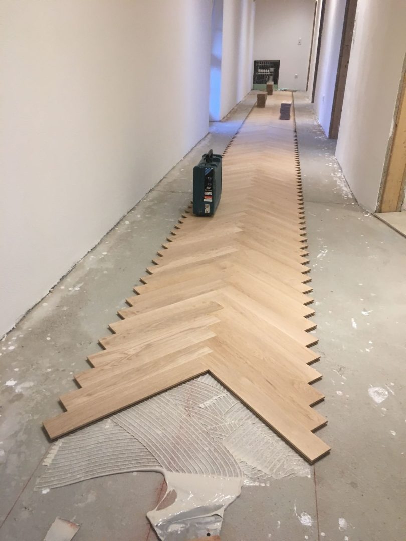 Eures • Holzfußbodenverlegung im Fischgrätmuster auf einem Rohboden.