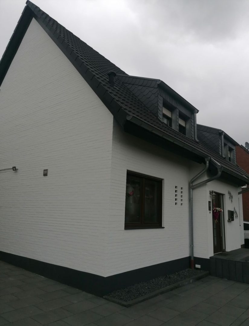 Eures • Weißes Einfamilienhaus mit schwarzem Dach und modernem Design.