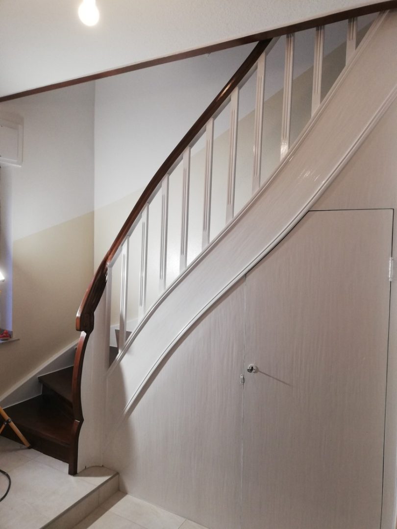 Eures • Blick auf elegante Holztreppe mit weißen Geländern.